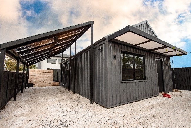 This Adelaide home looks like a black A-framed house from the street. The roof of the carport has solar panels which are east-facing. 