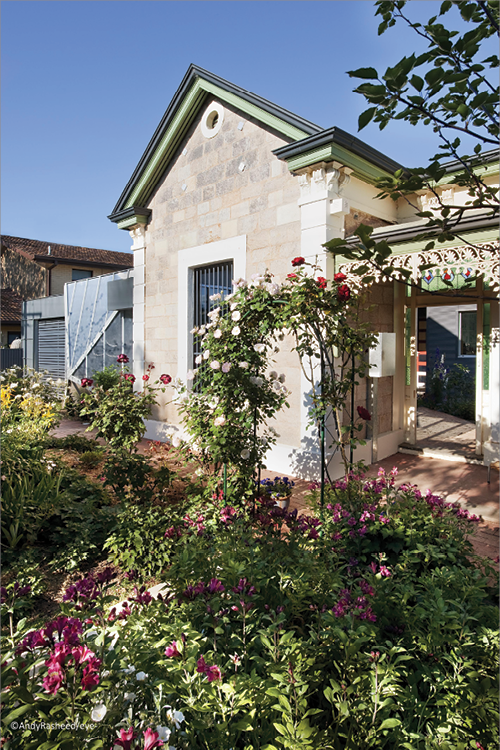 A heritage-style façade and garden, with lots of roses in the foreground.