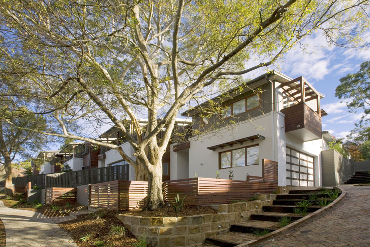 A street of modern two-storey townhouses with modest courtyards, landscaped gardens and natural shading. 