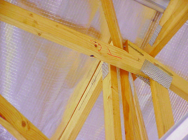 A photo shows reflective foil insulation secured above the timber frame of a house.